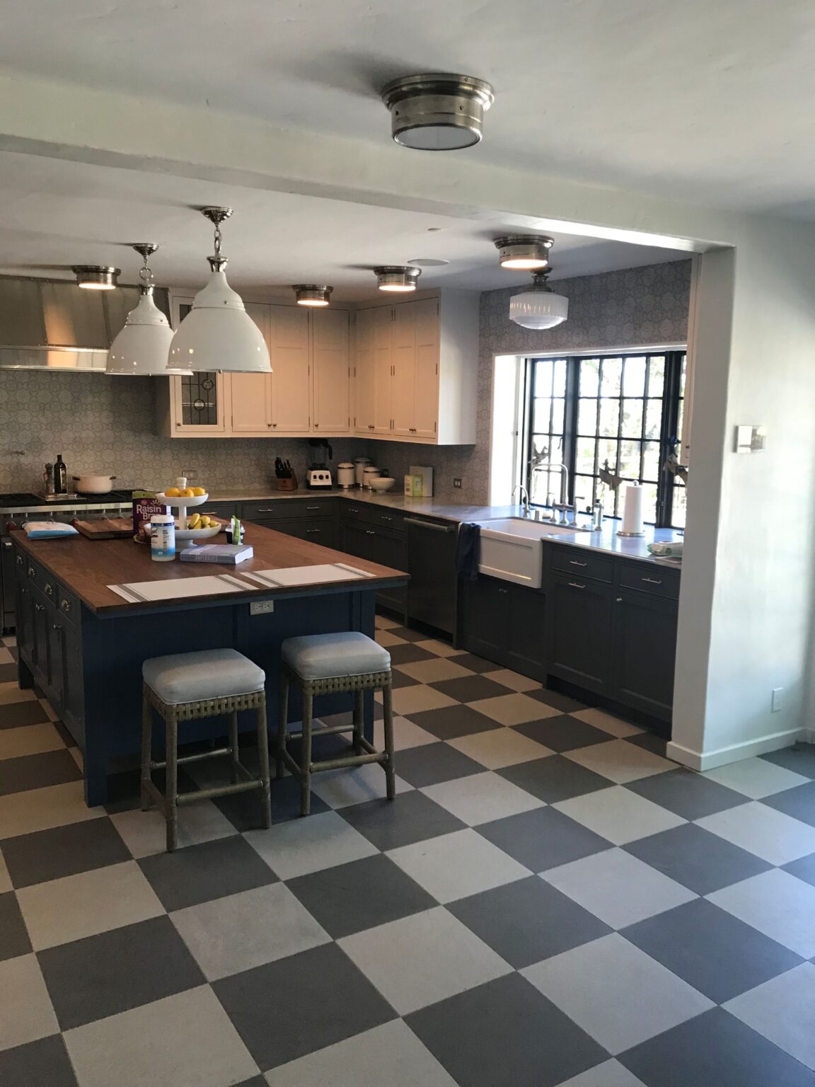 Kitchen with navy lower cabinets, a walnut-topped island, a farmhouse sink and a checkerboard floor