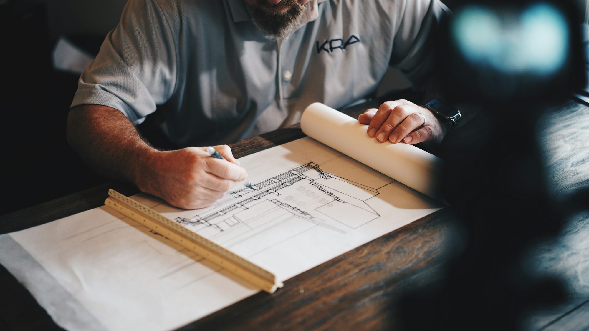 Architect reviewing floor plans with a scale ruler on a desk