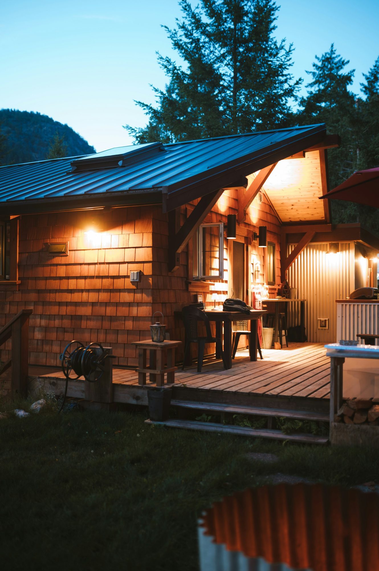 Finished backyard cottage with a lit deck at dusk