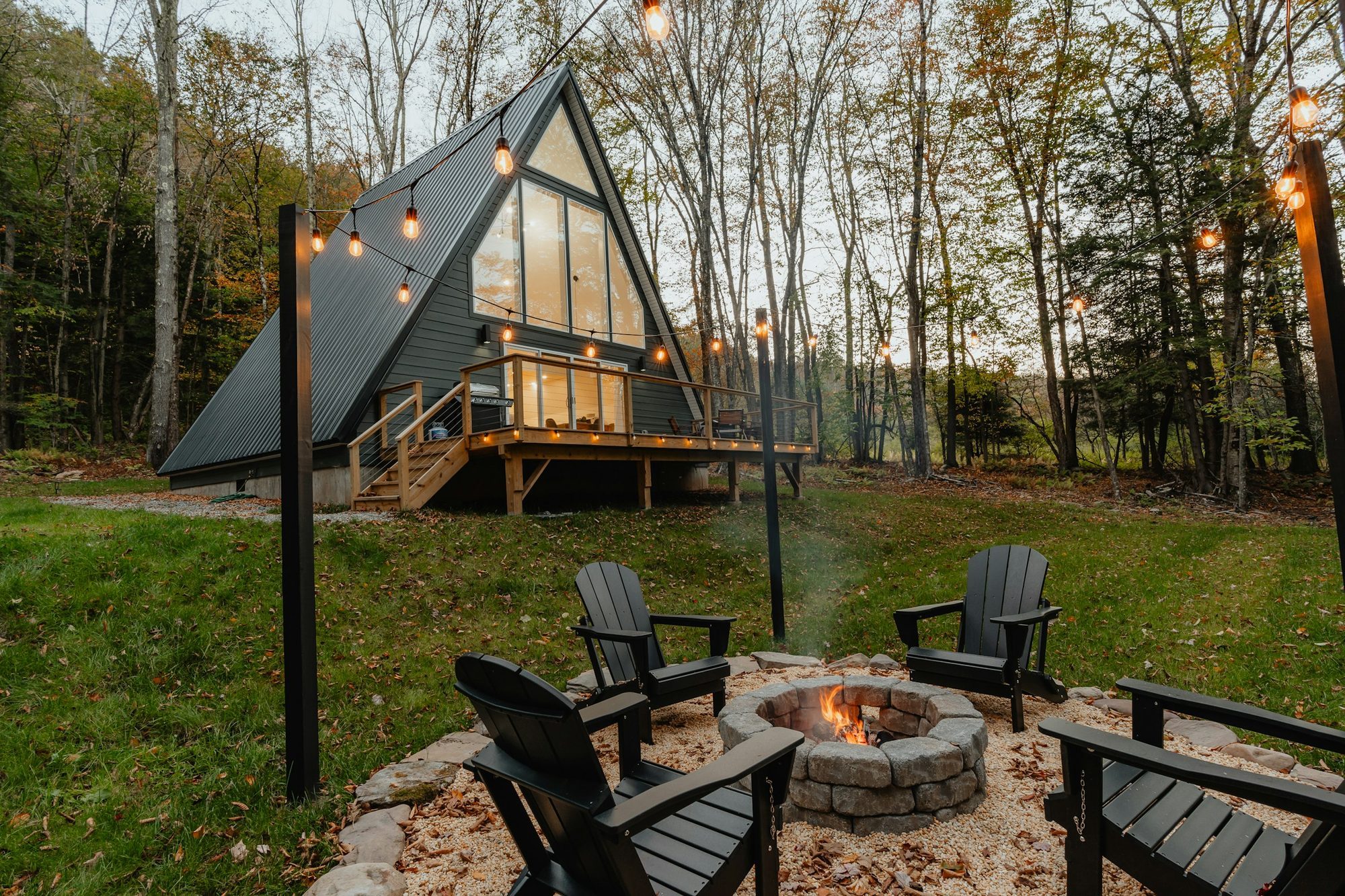 Small detached A-frame cottage in a yard with a fire pit and outdoor seating