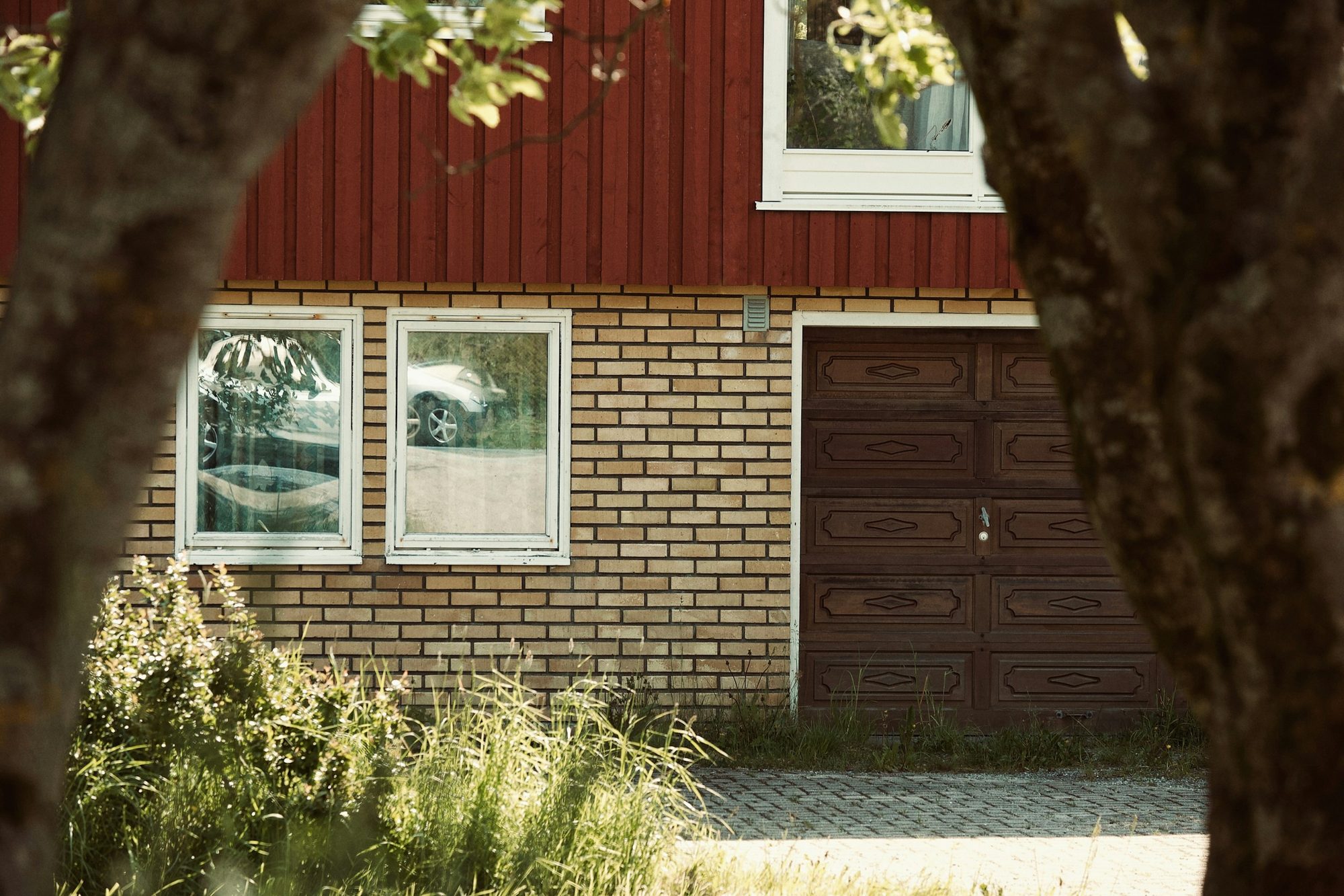 Residential garage exterior with brick and a brown garage door