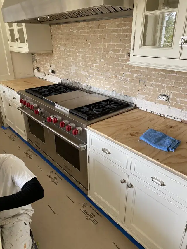 Kitchen remodel in progress with range set and white shaker cabinets