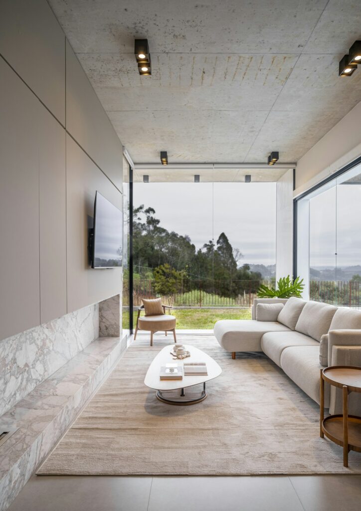 Floor-to-ceiling corner windows overlooking trees and hills