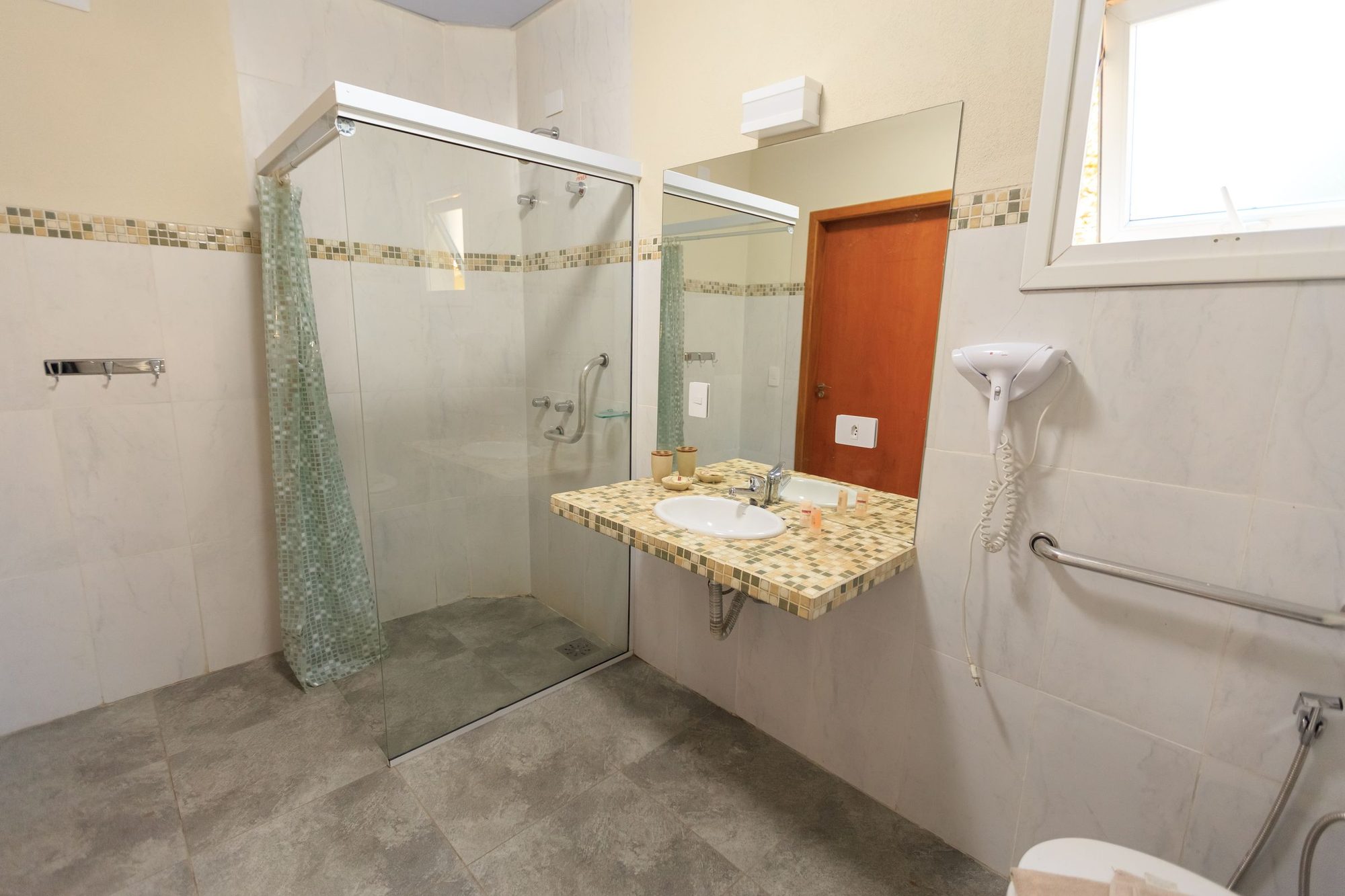 Accessible bathroom with a low-threshold glass shower, grab bars, and a wall-hung vanity