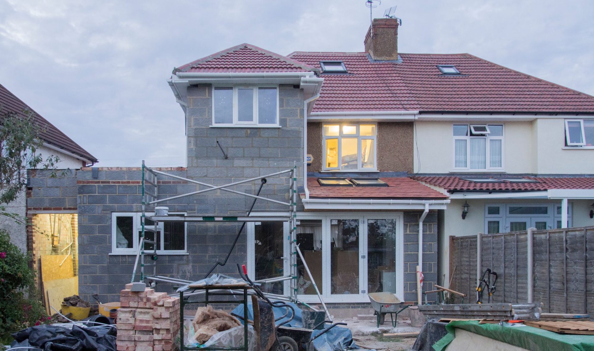 Rear home addition under construction, tied into the existing house with new walls, windows, and glass doors