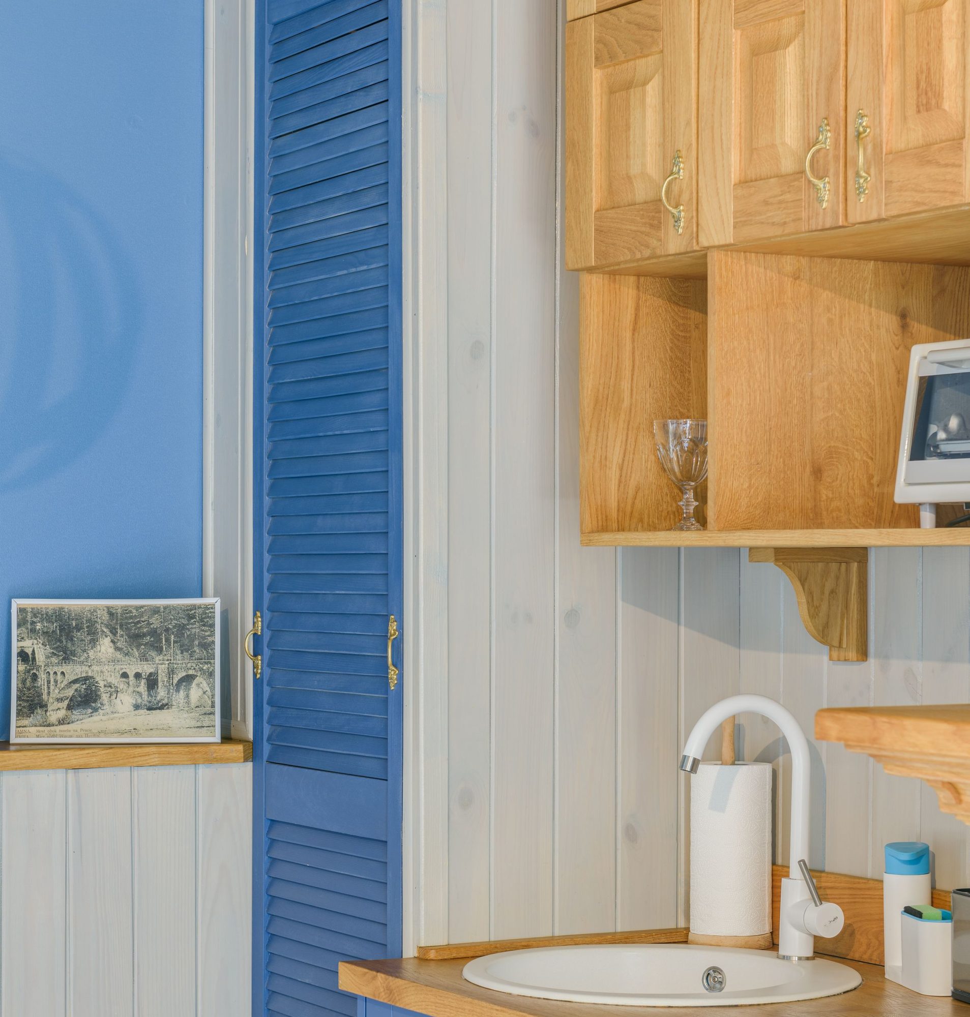 Compact kitchenette with blue lower cabinets, a wood countertop, a small sink, and open shelving