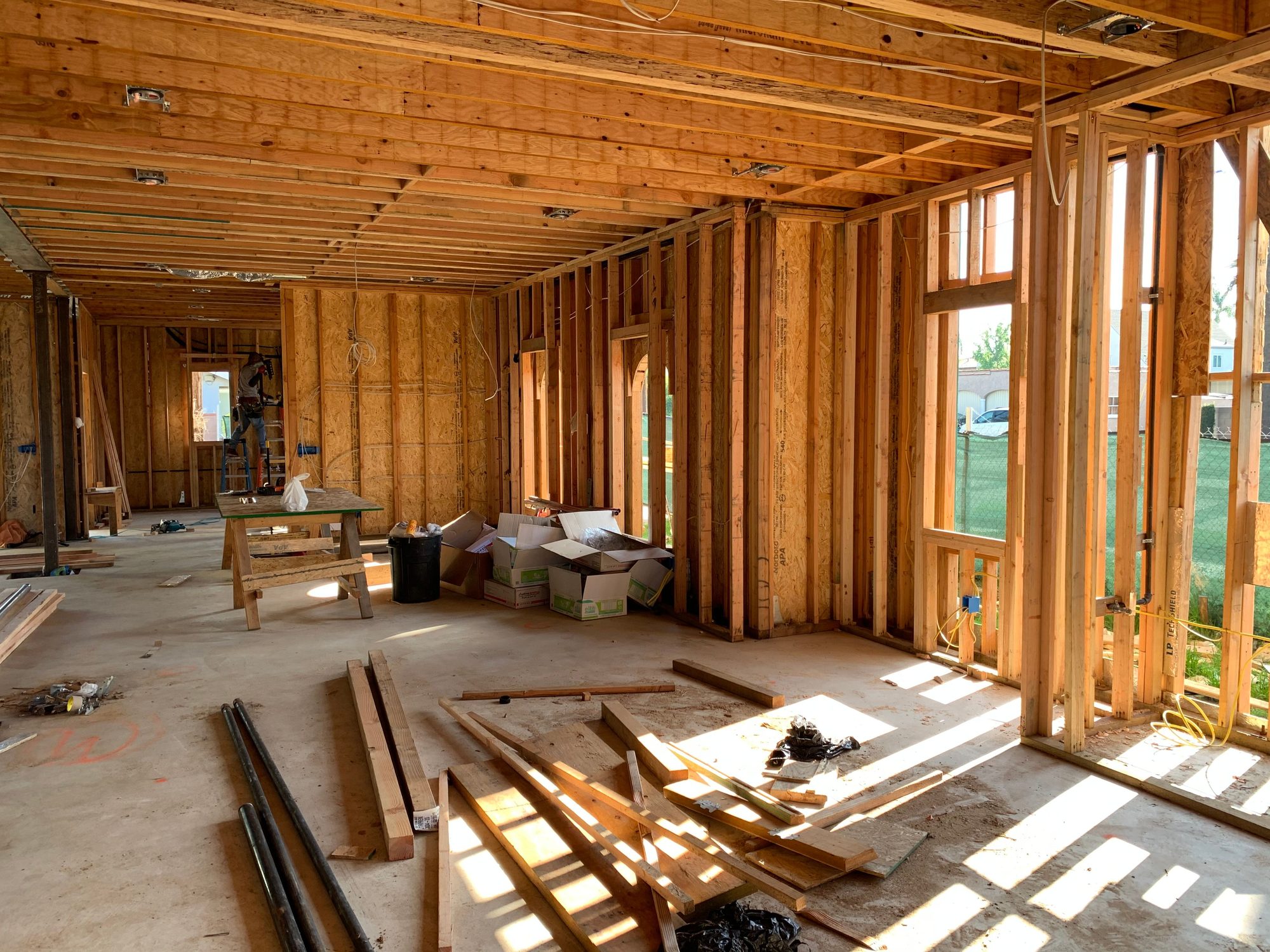 Room under construction with exposed wall studs, yellow electrical cable, and a concrete slab floor