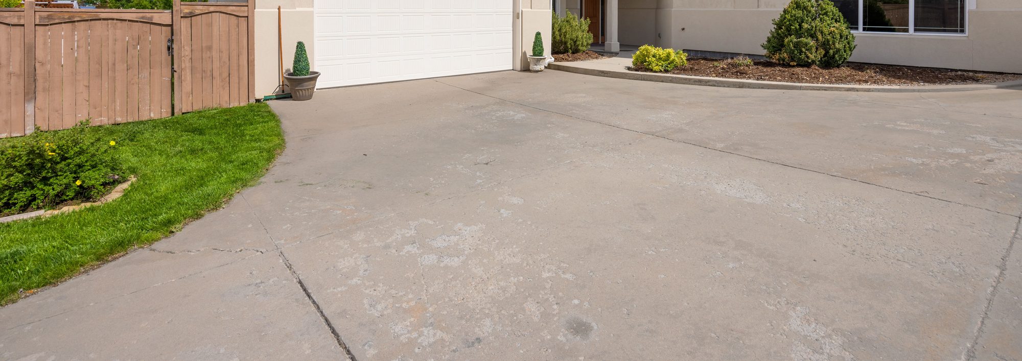 Wide concrete driveway beside a two-car garage door on a suburban home