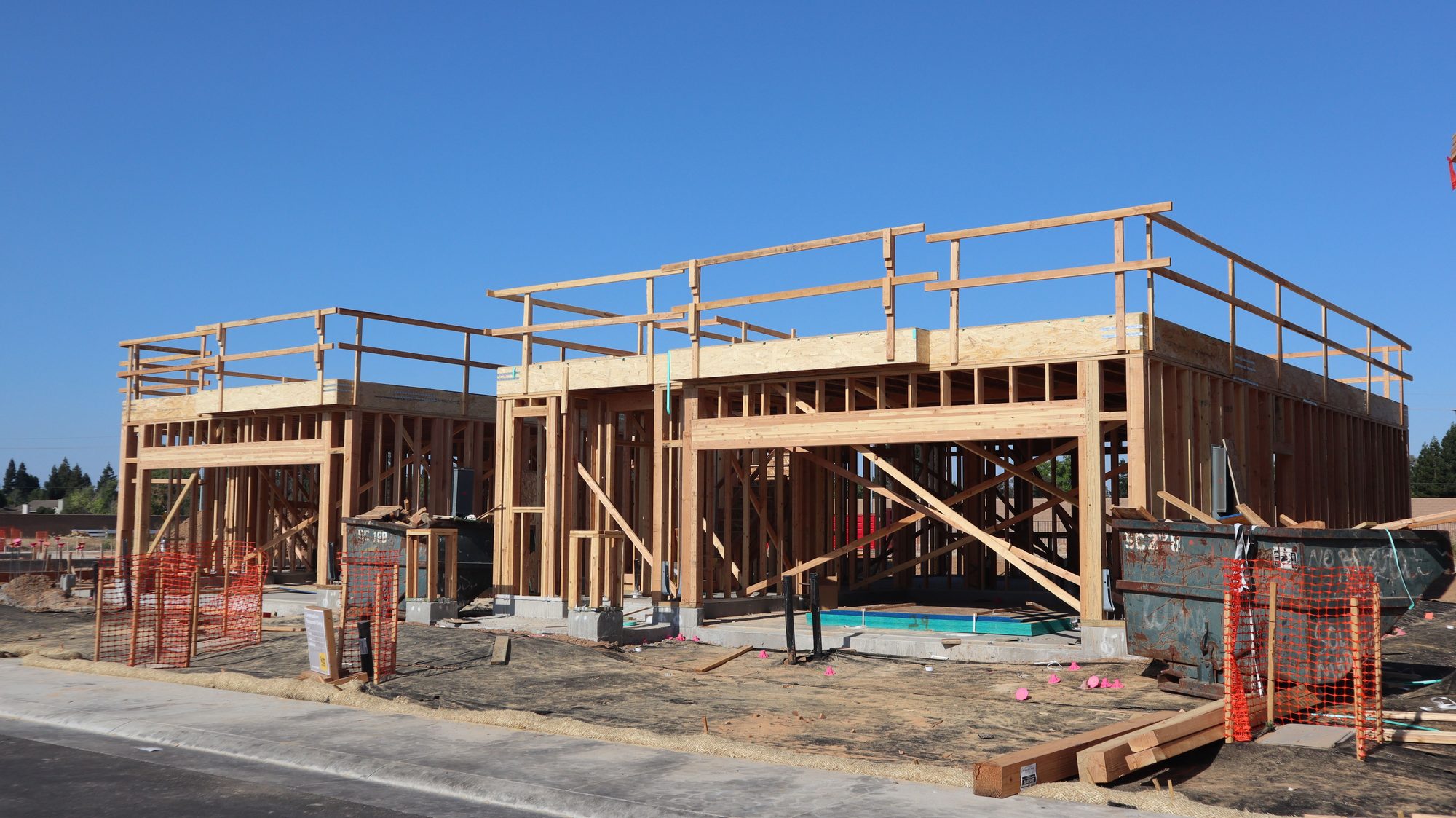Two small wood-framed buildings under construction on concrete slabs