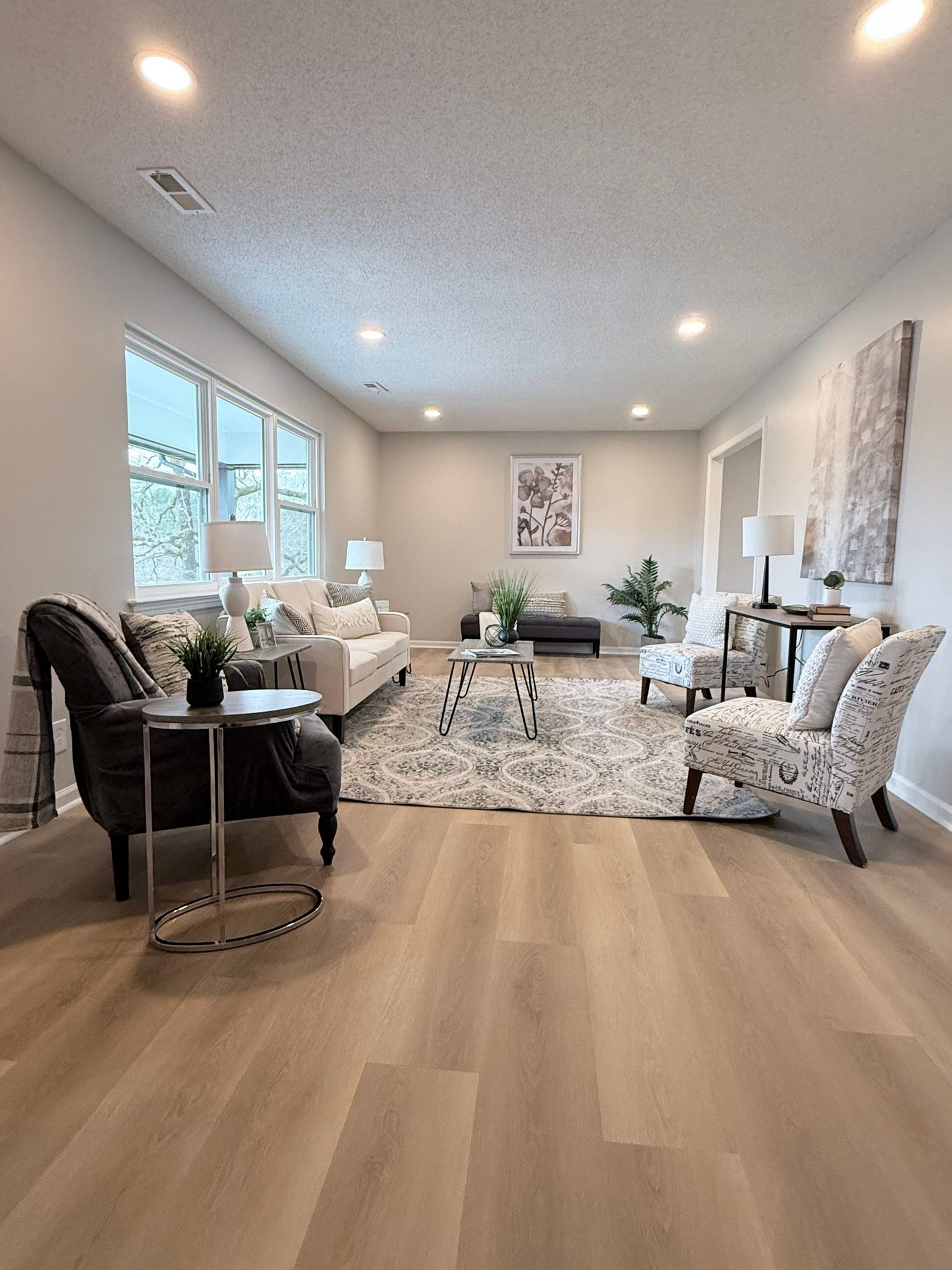 Bright living room in a lower-level mother-in-law suite finished by Peaceful Haven Homes in Chattanooga, with large windows, recessed lights, and light plank floors