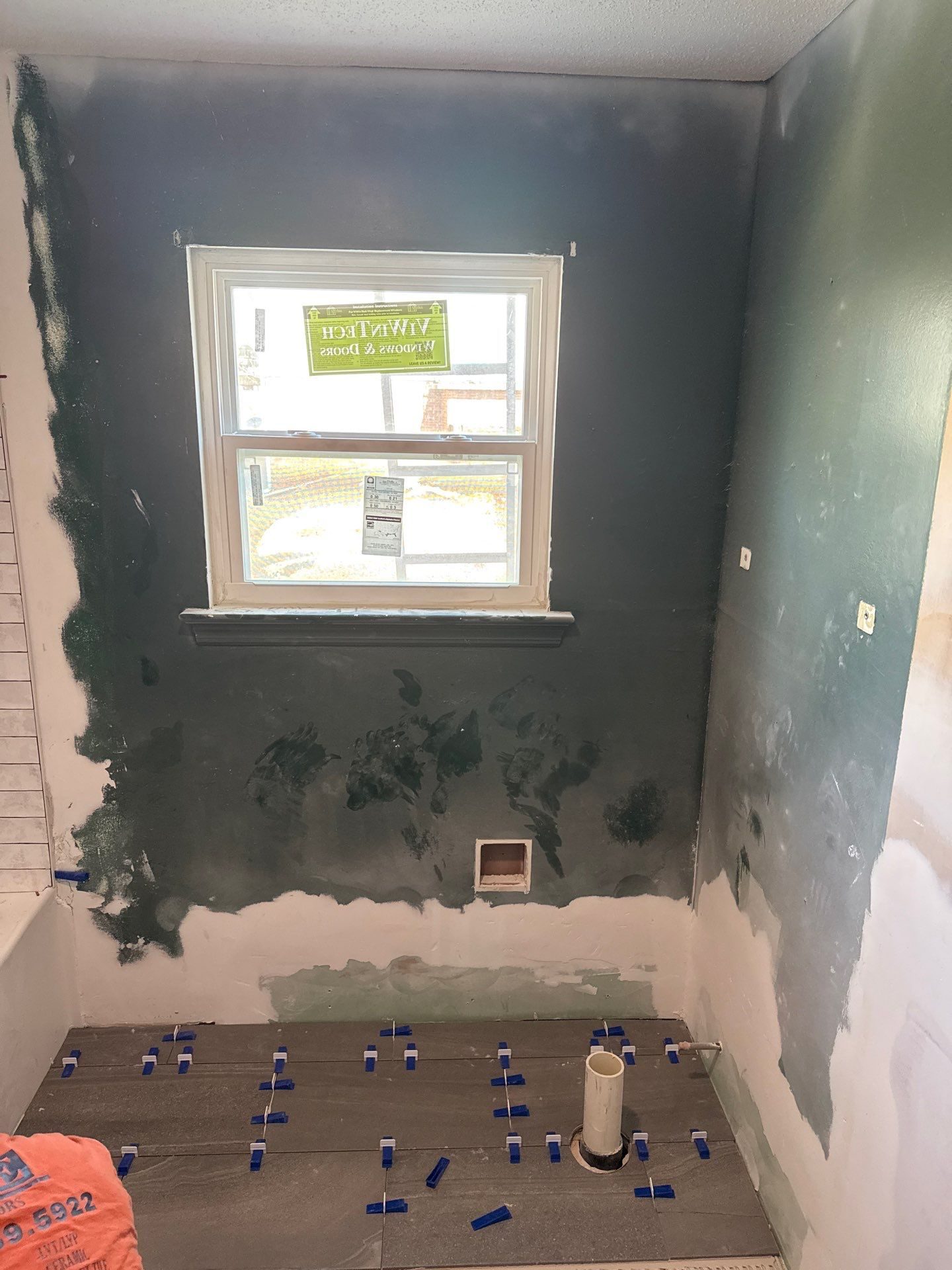 Lower-level suite bathroom in progress by Peaceful Haven Homes with sealed wet walls around the tub and floor tile laid out before setting