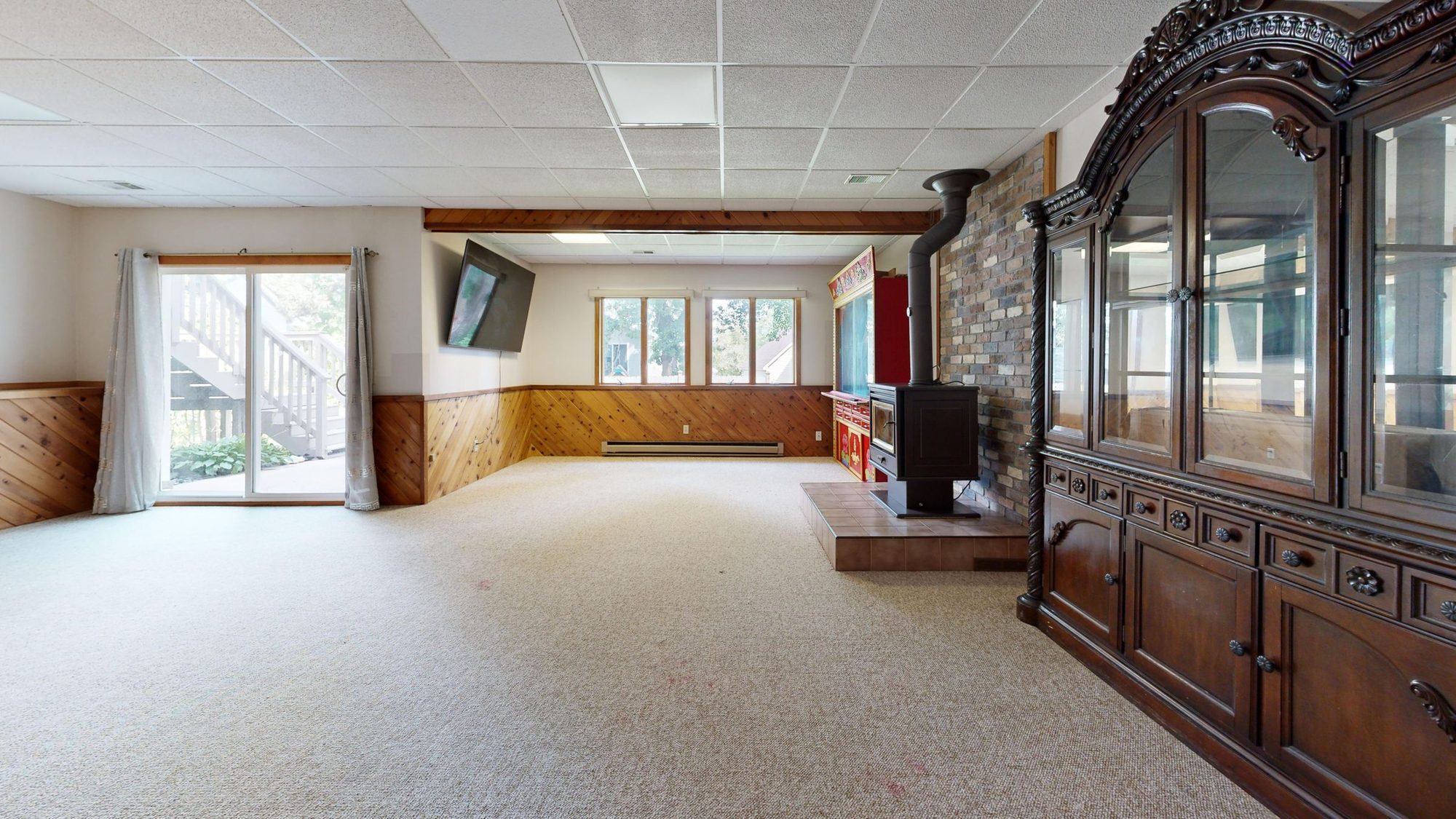 Finished walk-out basement family room with carpet, wood wainscoting, a fireplace, and a sliding glass door to the yard